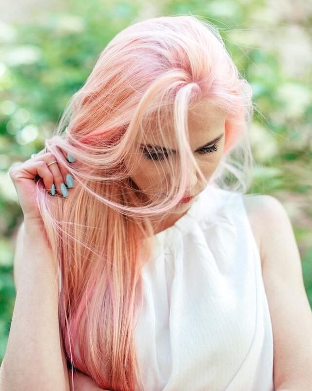 Eine helle blonde Frau mit pink getönten Haaren.